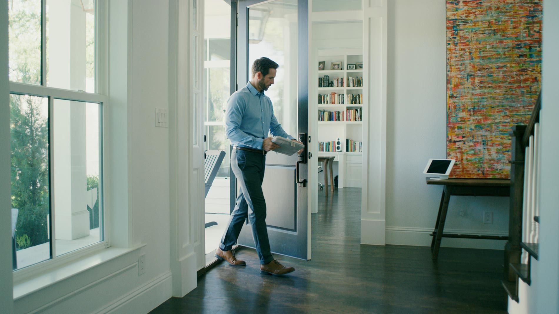 Man entering a modern home carrying a tablet