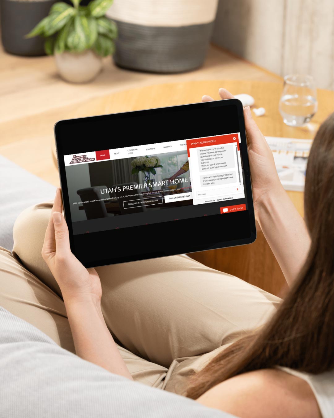 Person holding a tablet displaying a home automation website with an open chat window