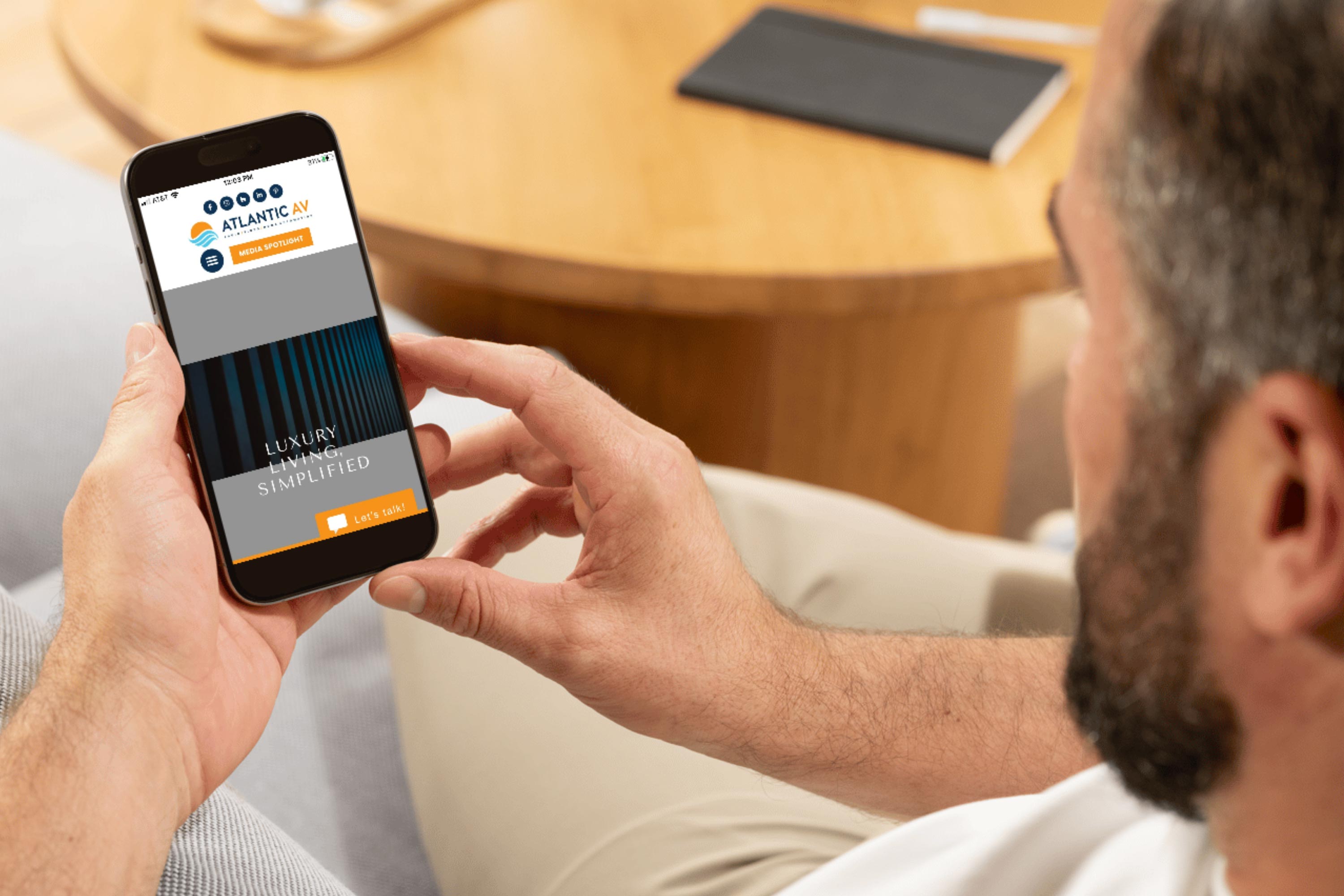 Close up of a person holding a smartphone showing a luxury home services website